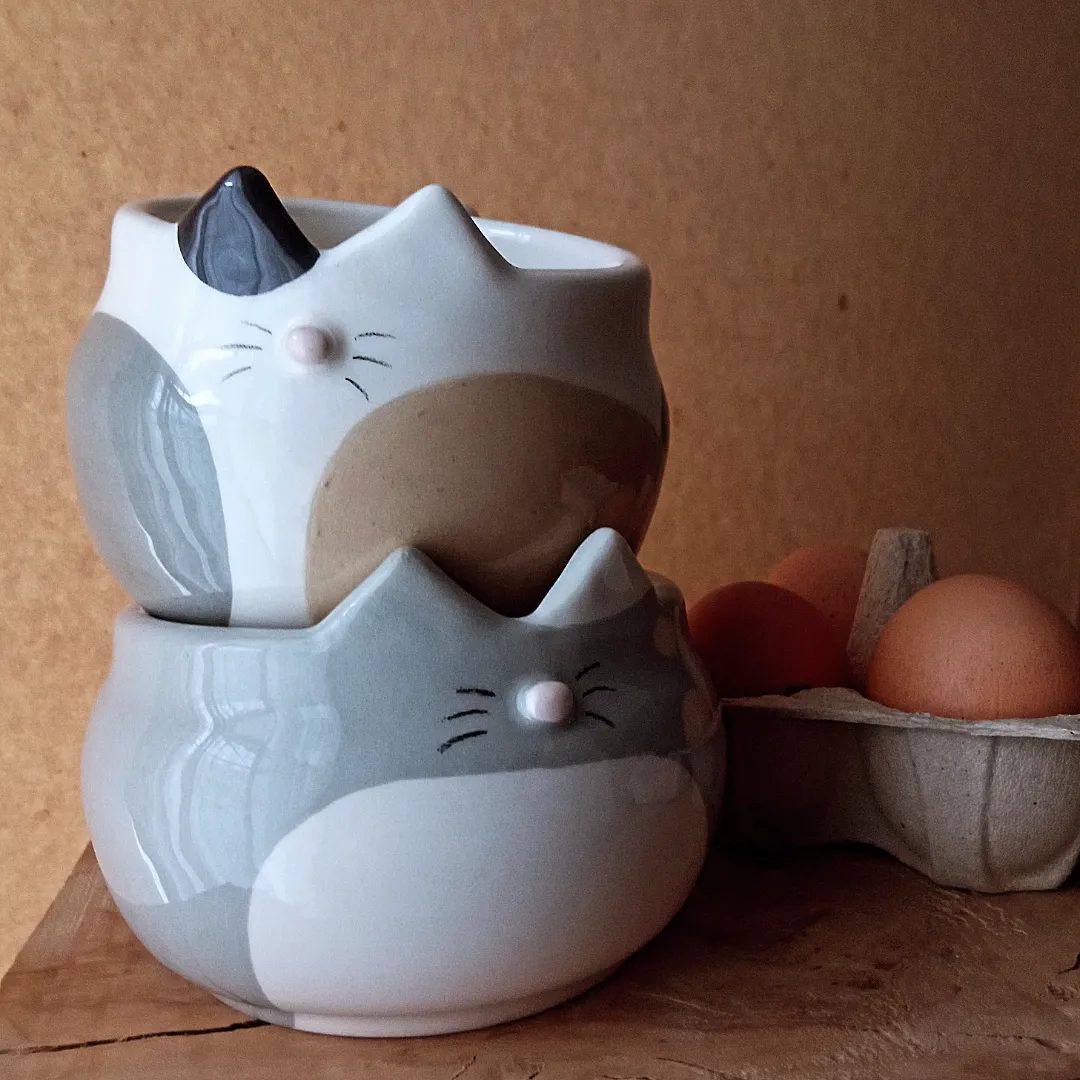 Due tazze-gatto smaltate, grigie e bianche, impilate